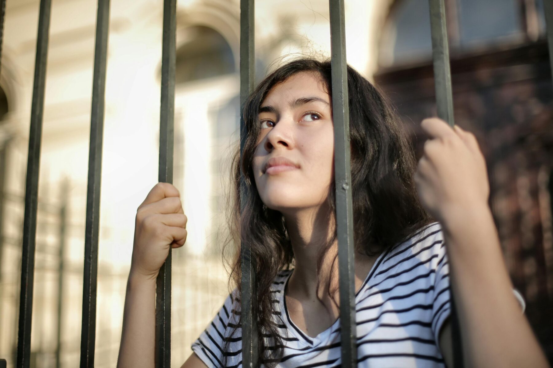 féminisme carcéral et féminisme anticarcéral. Une femme se tient derrière des barreaux de prison.